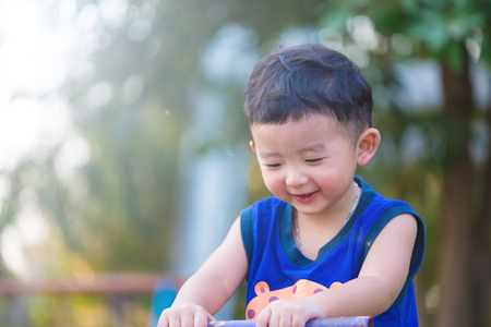Asian kid riding seesaw board at the playground under sunlight,の写真素材