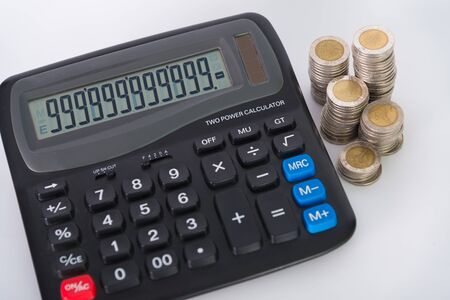 Stack of money in the form of coins and calculator on white background. saving concept. shallow focusの写真素材
