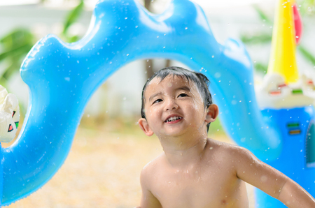 Asian kid playing in inflatable baby pool. Boy swim and splash in colorful swimming pool with water toys on hot summer day. shallow focusの写真素材
