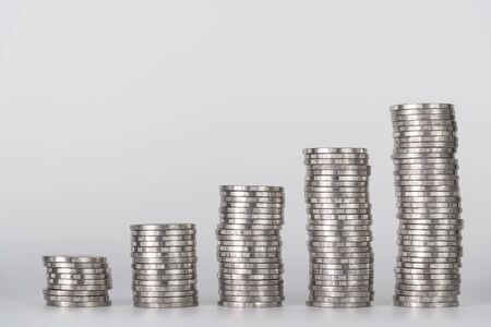 Savings, increasing columns of coins, piles of coins arranged as a graph on white background,...