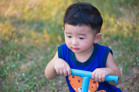 Sad kid play Â teeter-totter  at the playground under sunlight, in kindergarten or preschool. shallow Focusの写真素材
