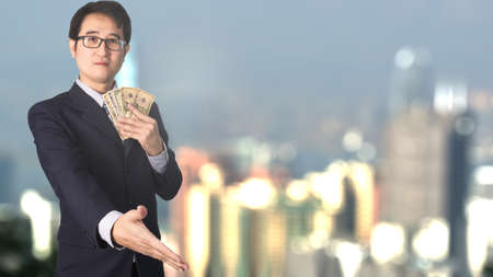 Double exposure of businessman holding money and shaking hand on blurred building and world...