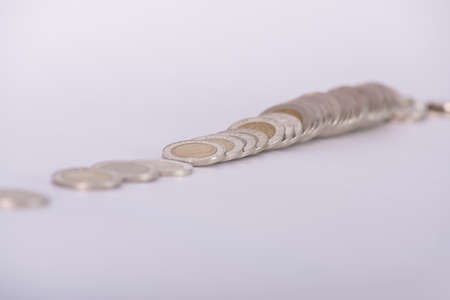 Stack of coins arranged on white background, business idea, shallow focus.