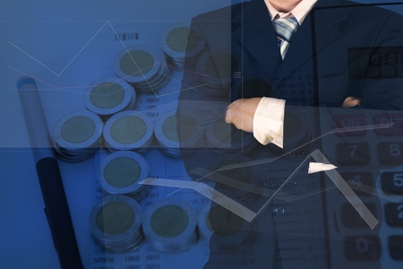 Double exposure of businessman arms crossed with stack of coins as house shape and calculator on the account book background. financial graph and banking, saving and loan for house concept.の写真素材