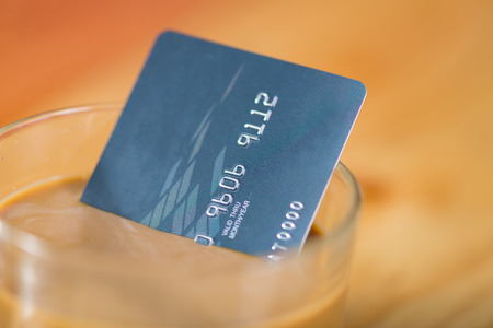 Credit card and glass of hot coffee on wooden table in the morning, soft tone. shallow focusの写真素材