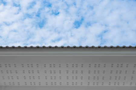 White eaves with ceiling and roof of modern house against blue sky under sun light.