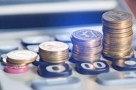 Savings, increasing columns of gold coins, piles of coins arranged as a graph on calculator, business idea, shallow focus. soft toneの写真素材