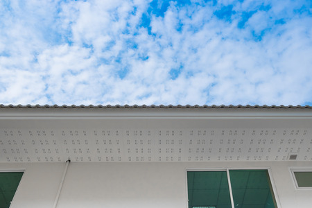 White eaves with ceiling and roof of modern house against blue sky under sun light.
