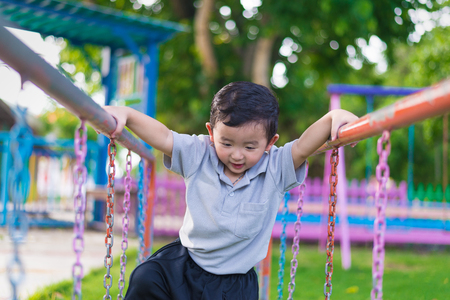 Asian boy hang the metal bar for balance at outdoor playground.の写真素材