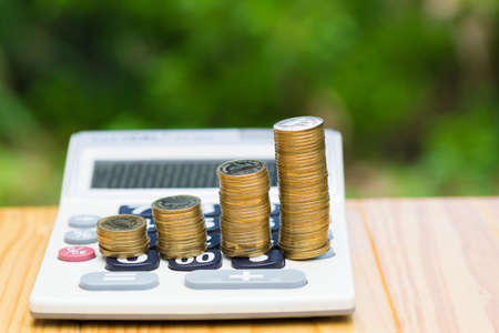 Savings, Growing coins and calculator on wood with green tree bokeh background. Financial growth,...