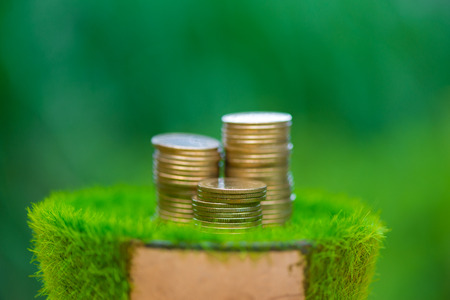 Stack of gold coin  on artificial grass in pot, with green nature background. shallow focus. business success and banking concept.の写真素材