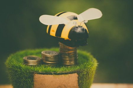 Stack of gold coin  on artificial grass in pot, on wooden table with green nature background in vintage tone. shallow focus. business success and banking concept.の写真素材