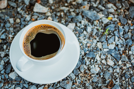 White cup of hot coffee with white plate on gray stone ground nature background in vintage tone. shallow focusの写真素材