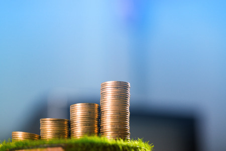 Stack of gold coin  on artificial grass in pot, on wooden table. shallow focus. business success and banking concept.の写真素材