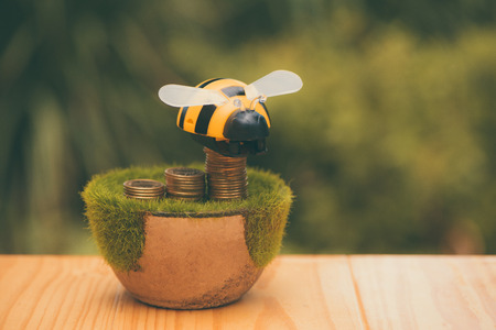 Stack of gold coin  on artificial grass in pot, on wooden table with green nature background in vintage tone. shallow focus. business success and banking concept.の写真素材