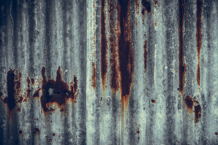 Old rusty corrugated tin zinc metal wall in vintage tone with vignetting.の写真素材