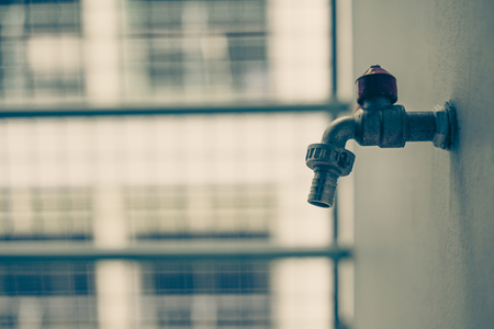 Old faucet on concrete wall terrace with sun light. vintage tone.の写真素材