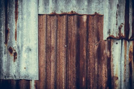 Old rusty corrugated tin zinc metal wall in vintage tone with vignetting.の写真素材