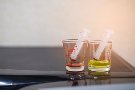 syringe with medicine syrup in a Pharmaceutical glass measuring cup for kid patient, selective focus.の写真素材