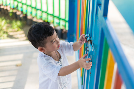 Sad lonely Asian kid behind the grid or fence and trying to escape. shallow DOFの写真素材