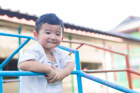 Asian boy hang the metal bar for balance at outdoor playground. Shallow DOFの写真素材