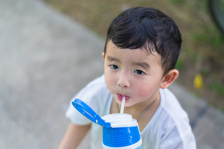 Close up of Asian baby boy drinking water with straw, shallow DOFの写真素材