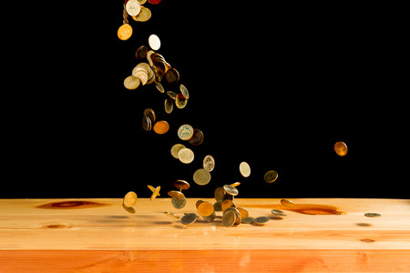Falling gold coins money on wooden table with black wall, copy space, business wealth concept. thin focusの写真素材