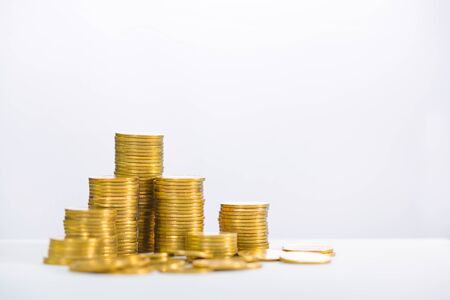 Columns of gold coins, piles of coins arranged on white background, business banking idea, shallow focus.の写真素材