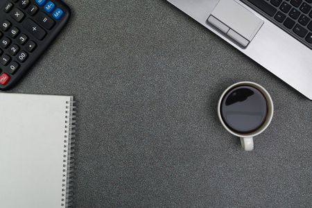 Laptop computer or notebook, calculator and cup of coffee  on gray color modern working table or desk, work space with copy space top view.の写真素材