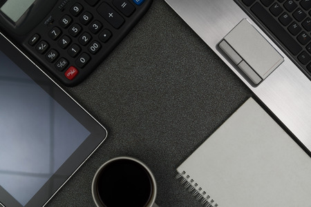 Laptop computer or notebook, note and cup of coffee  on gray color modern working table or desk,...