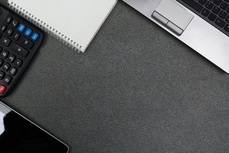 Laptop computer or notebook and other device, calculator and notepad on gray color modern working table or desk, work space with copy space top view.の写真素材