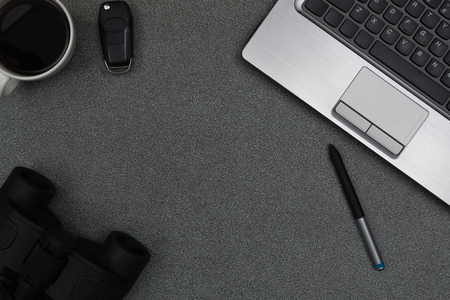 Laptop computer or notebook, binocular and cup of coffee on gray color modern working table or desk, work space with copy space top view.の写真素材