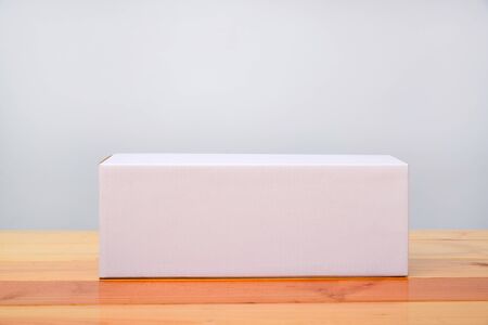 Empty Package white cardboard box mock up for long items on bright wooden table with copy space.の写真素材