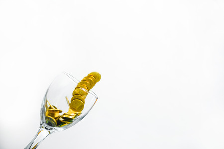 Golden coins splash in a glass of champagne on the wall background with copy space., saving money concept.の写真素材