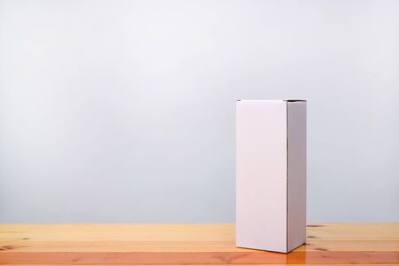Empty Package white cardboard box mock up for long items on bright wooden table with copy space.