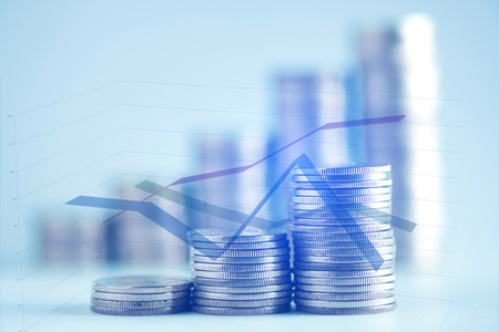 Double exposure of stacks of coins on working table with financial graph chart and copy space,...
