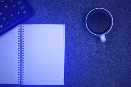 Calculator and cup of coffee with note on gray color modern working table or desk, work space with copy space top view. soft toneの写真素材