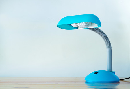 Blue desk lamp on wooden bright table with copy space.の写真素材