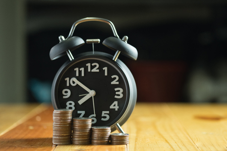 Alarm clock and step of coins stacks on working table, time for savings money concept, banking and business idea.の写真素材
