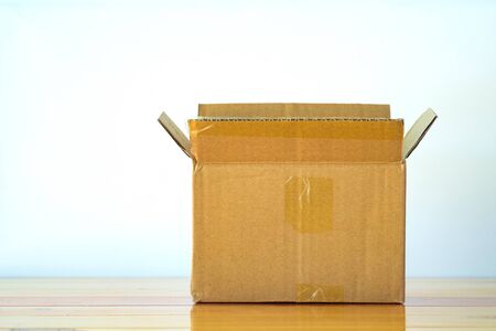 Empty opened old brown cardboard box for mock up on bright wooden table with copy space.