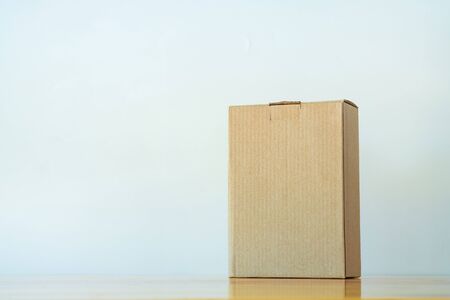 Empty closed brown cardboard box for mock up on bright wooden table with copy space.の写真素材