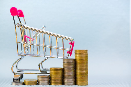 Step of stacks of coins and shopping cart or supermarket trolley on grey background, business finance shopping concept.の写真素材