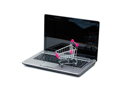 Shopping cart or supermarket trolley with laptop notebook on isolated white background and copy space, e-commerce and online shopping concept.の写真素材