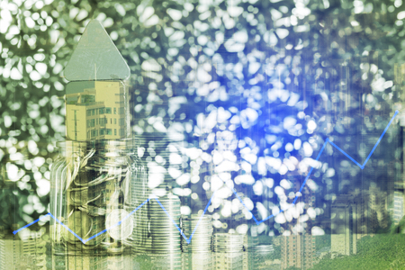 Double exposure of model house and coins stack with city background and financial graph, real estate investment and saving banking money finance concept.の写真素材