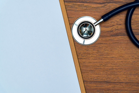 Stethoscope and clipboard with blank white paper sheet on bright wood table top view with copy space, health and concept.の写真素材