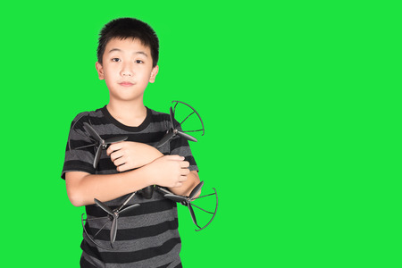 Asian boy holding drone or quad copter toy in hand, studio shot isolated on green background.の写真素材