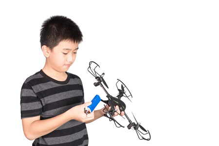 Asian boy holding and checking his drone or quad copter toy in hand, isolated on white background.