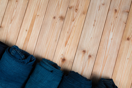 Roll Frayed jeans or blue jeans denim collection on rough wooden table background with copy space, old fashion style concept.の写真素材