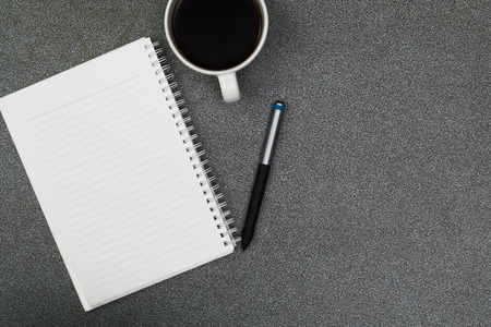 A cup of coffee with note and pen on gray color modern working table or desk, work space with copy space top view.の写真素材