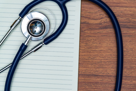 Stethoscope and notebook on bright wood table top view with copy space, health and concept.の写真素材